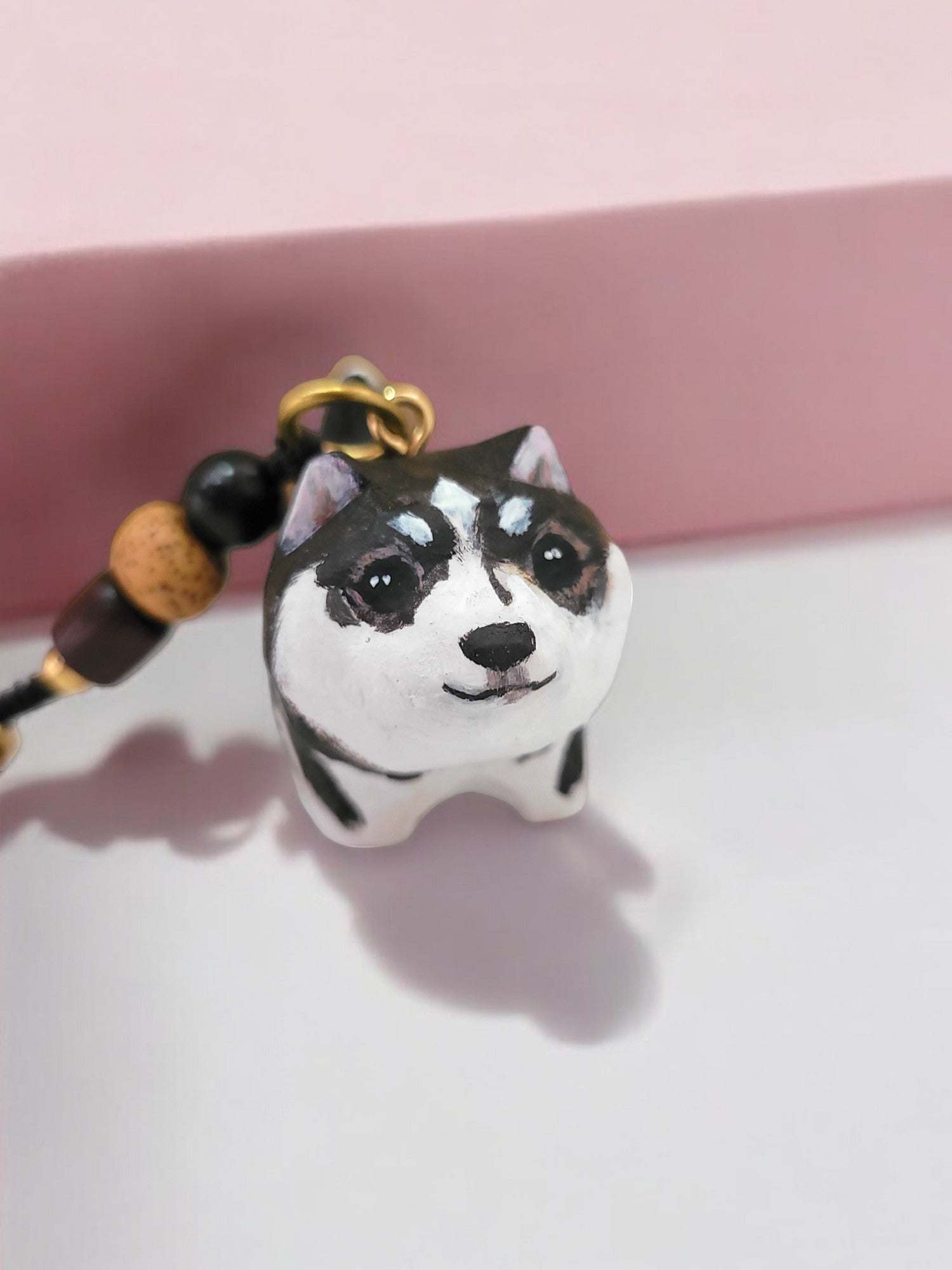 Hand-painted custom pet portrait keychain featuring a cute dog with beads on a black cord, front view.