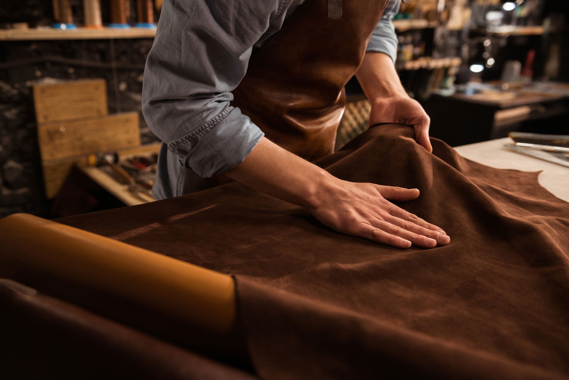 Hands of a craftsman working with leather in a workshop, highlighting the meticulous and high-quality craftsmanship involved in creating personalized pet products