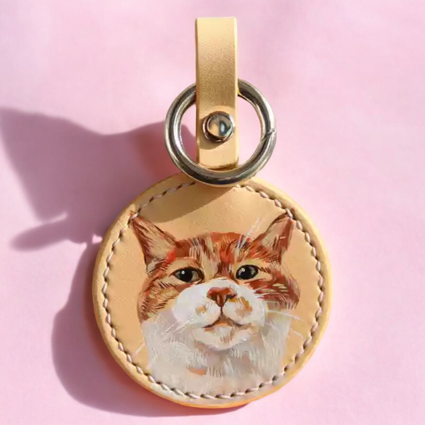 Hand-painted leather keychain with a lifelike portrait of an orange tabby cat, ideal for personalized pet accessories.