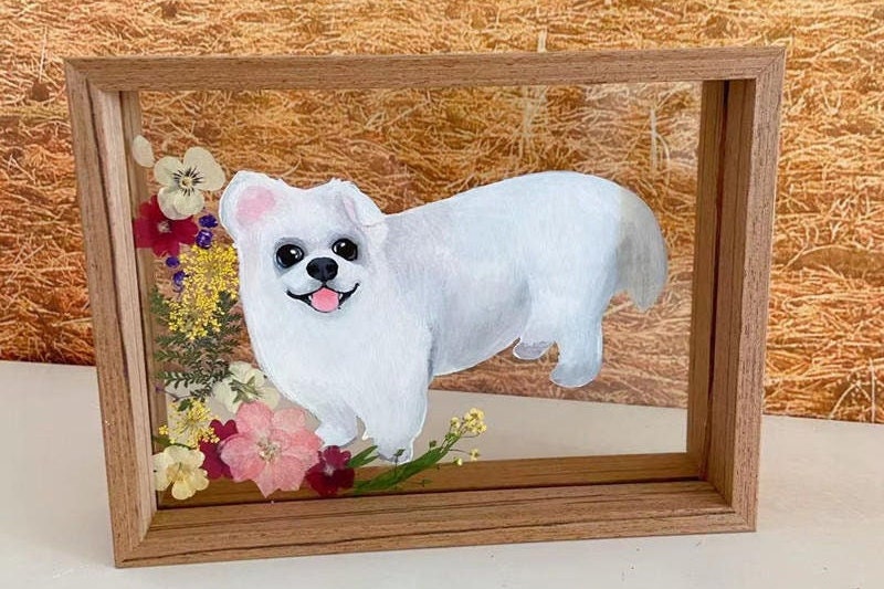 Custom pet portrait featuring a small dog with a flower crown, hand-painted on glass with a wooden frame.