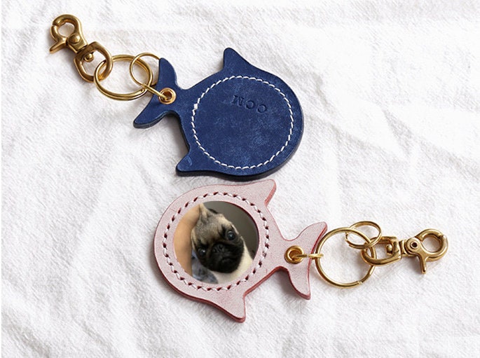 Fish shaped personalized and hand-crafted pet portrait of a dog keychain in blue and pink colors.