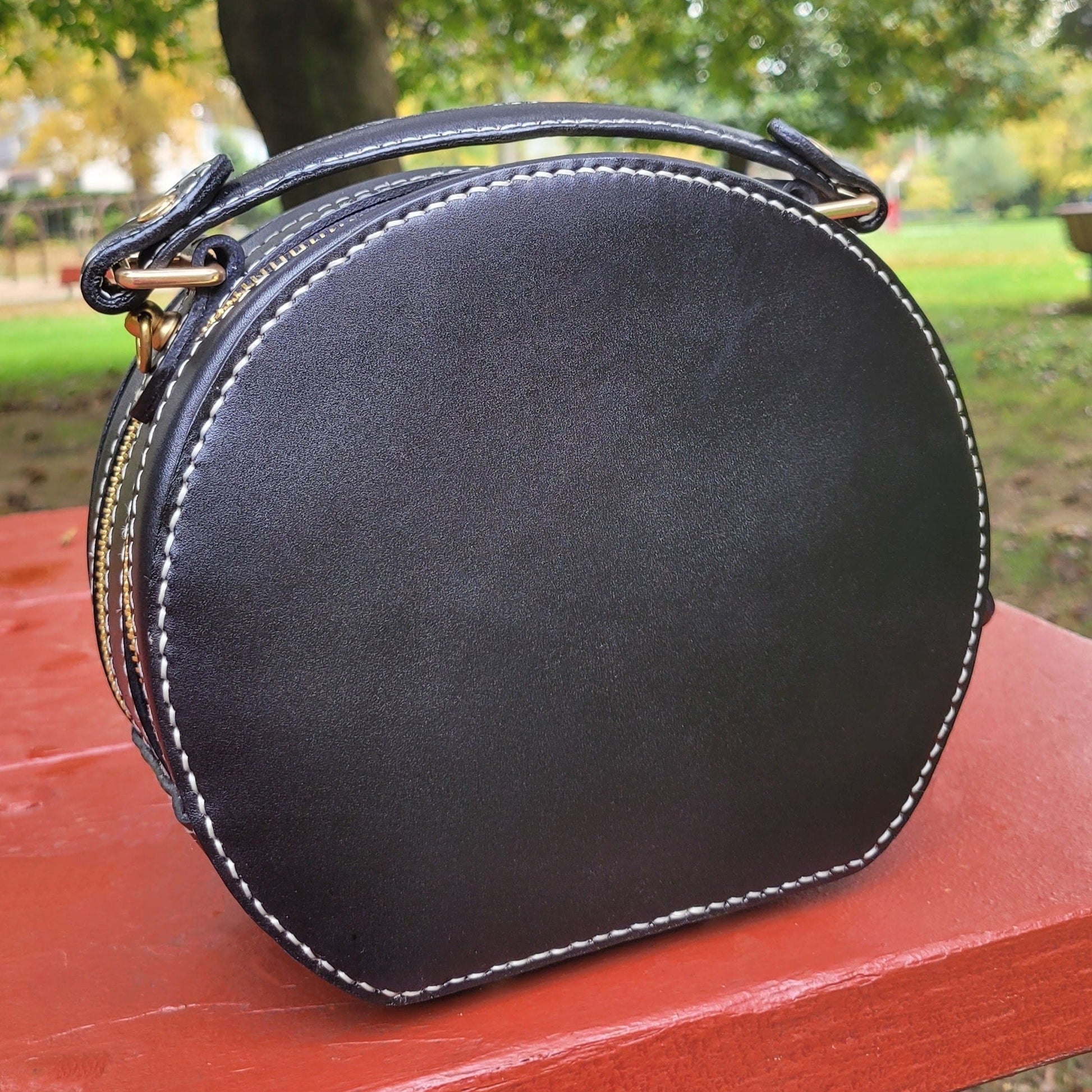 Back view of a round leather handbag with custom pet portrait painting