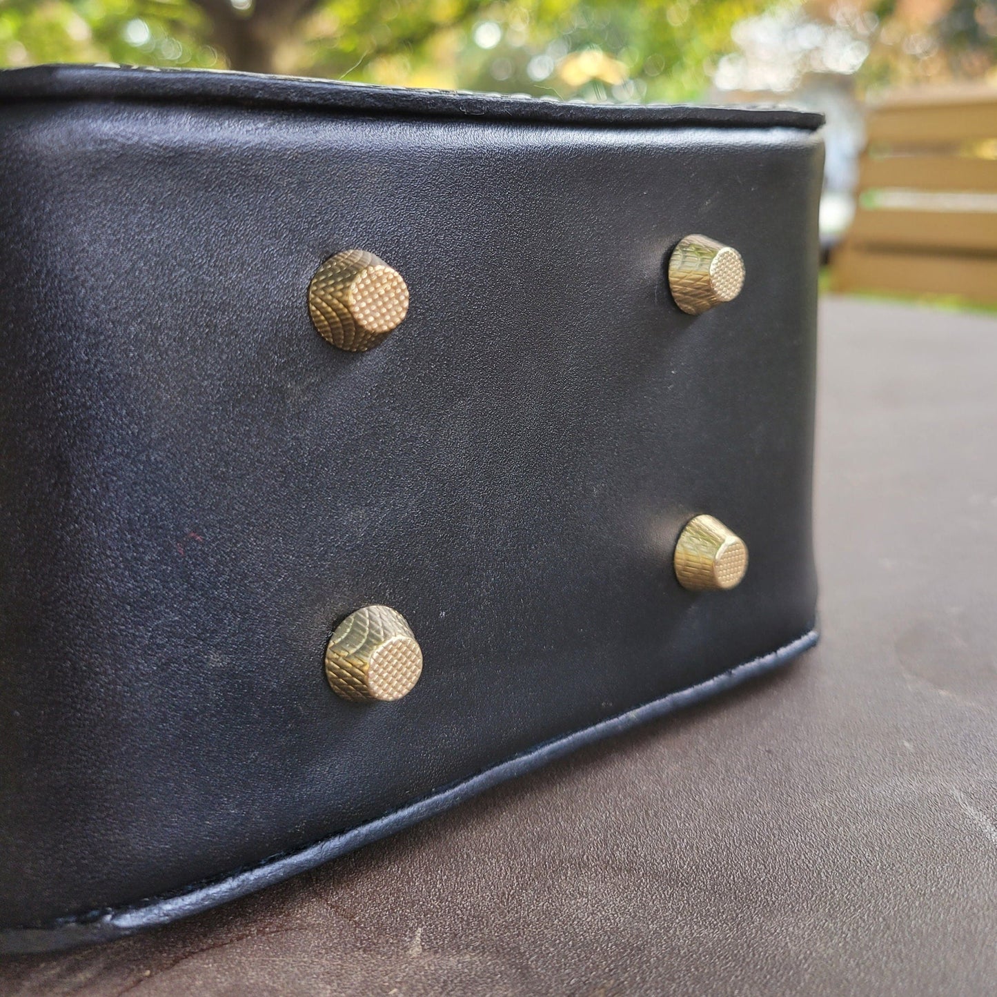 Bottom view of a leather handbag displaying the sturdy metal feet for stability