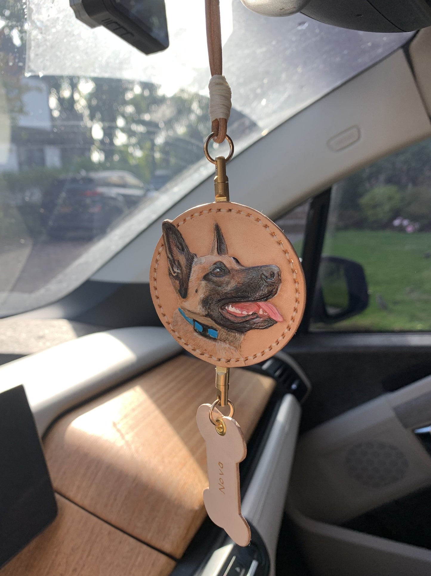 Front view close up of handcrafted customizable pet portrait car mirror charm with name tag