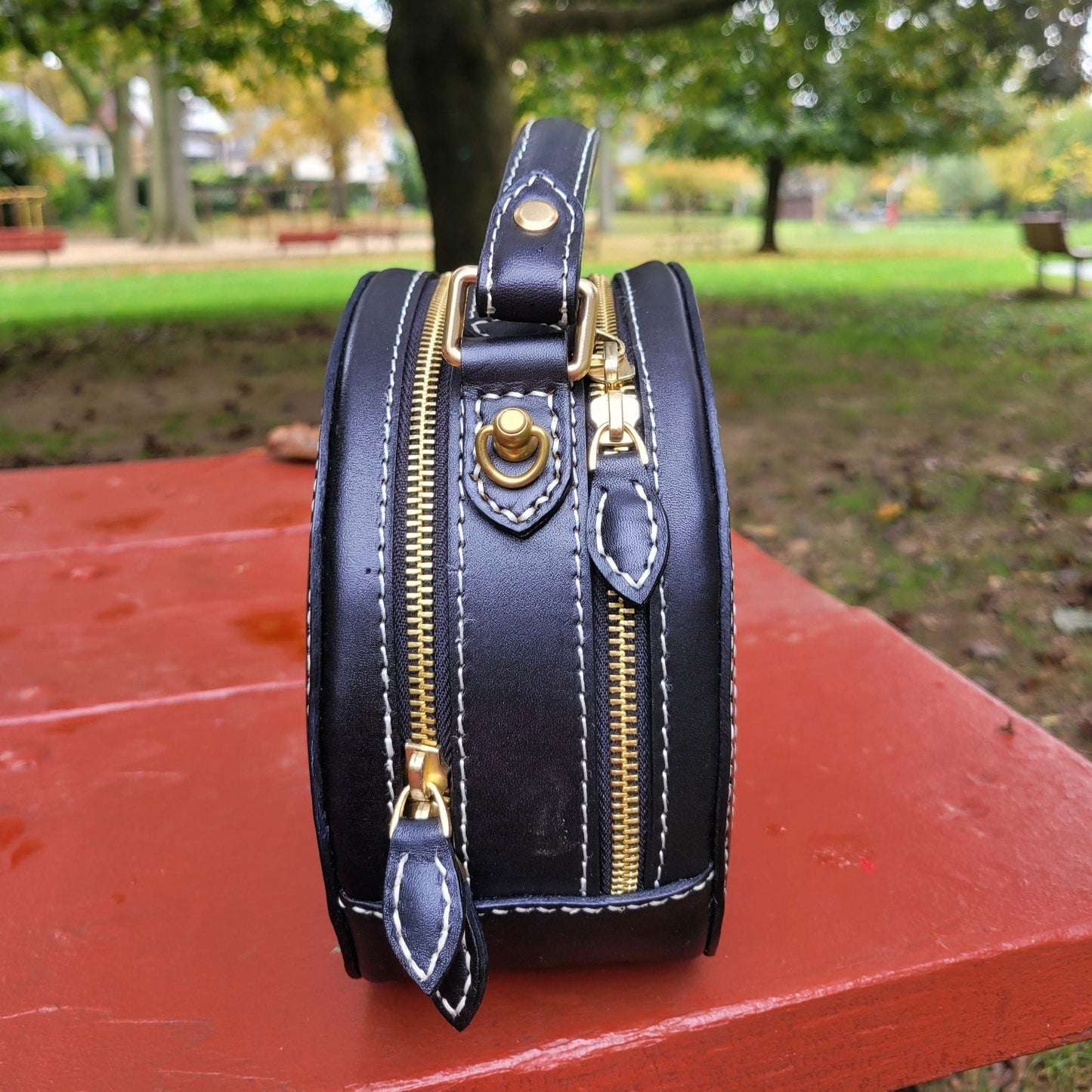 Side view of a black leather handbag showing the detailed stitching and custom painting