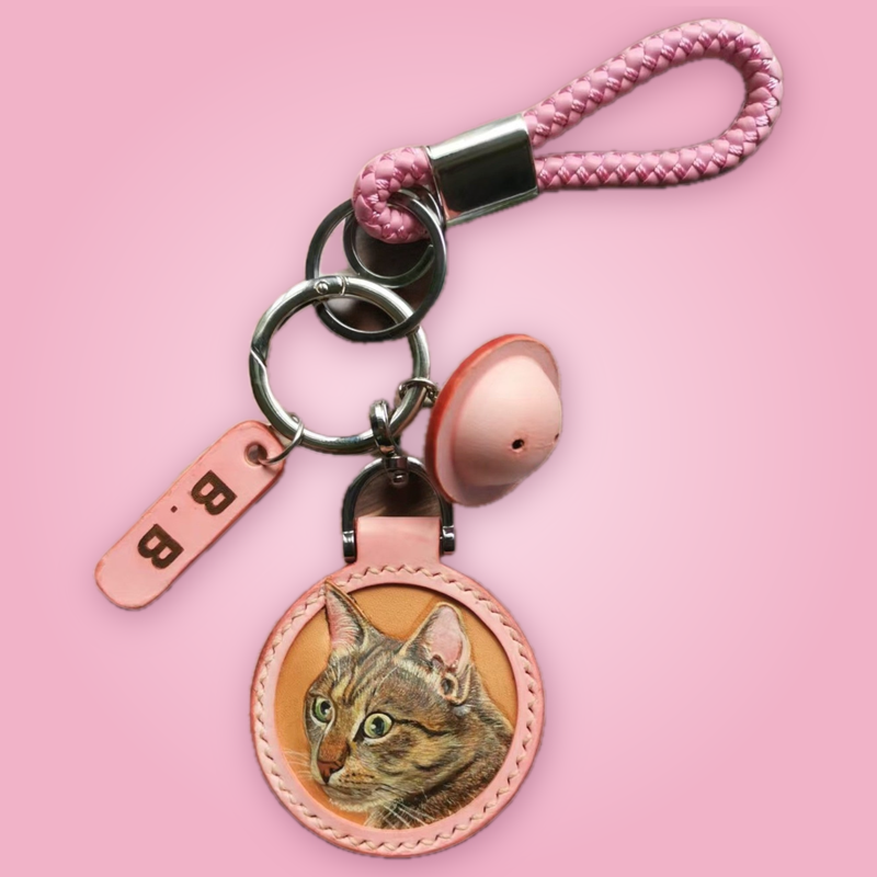Hand-carved leather pet keychain with custom pet portrait on a soft pink background
