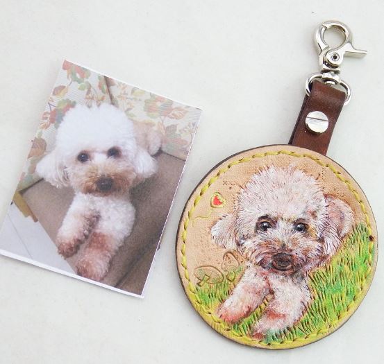 Custom hand-painted leather keychain with a portrait of a white poodle, shown with the original photo.
