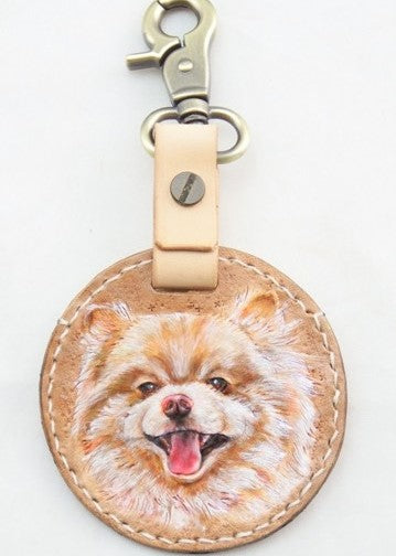 Custom hand-painted leather keychain with a portrait of a white dog wearing a red scarf