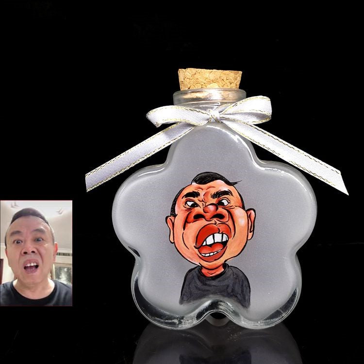 A humorous hand-painted caricature portrait of a man inside a flower-shaped sand bottle with a white ribbon tied on the cork.