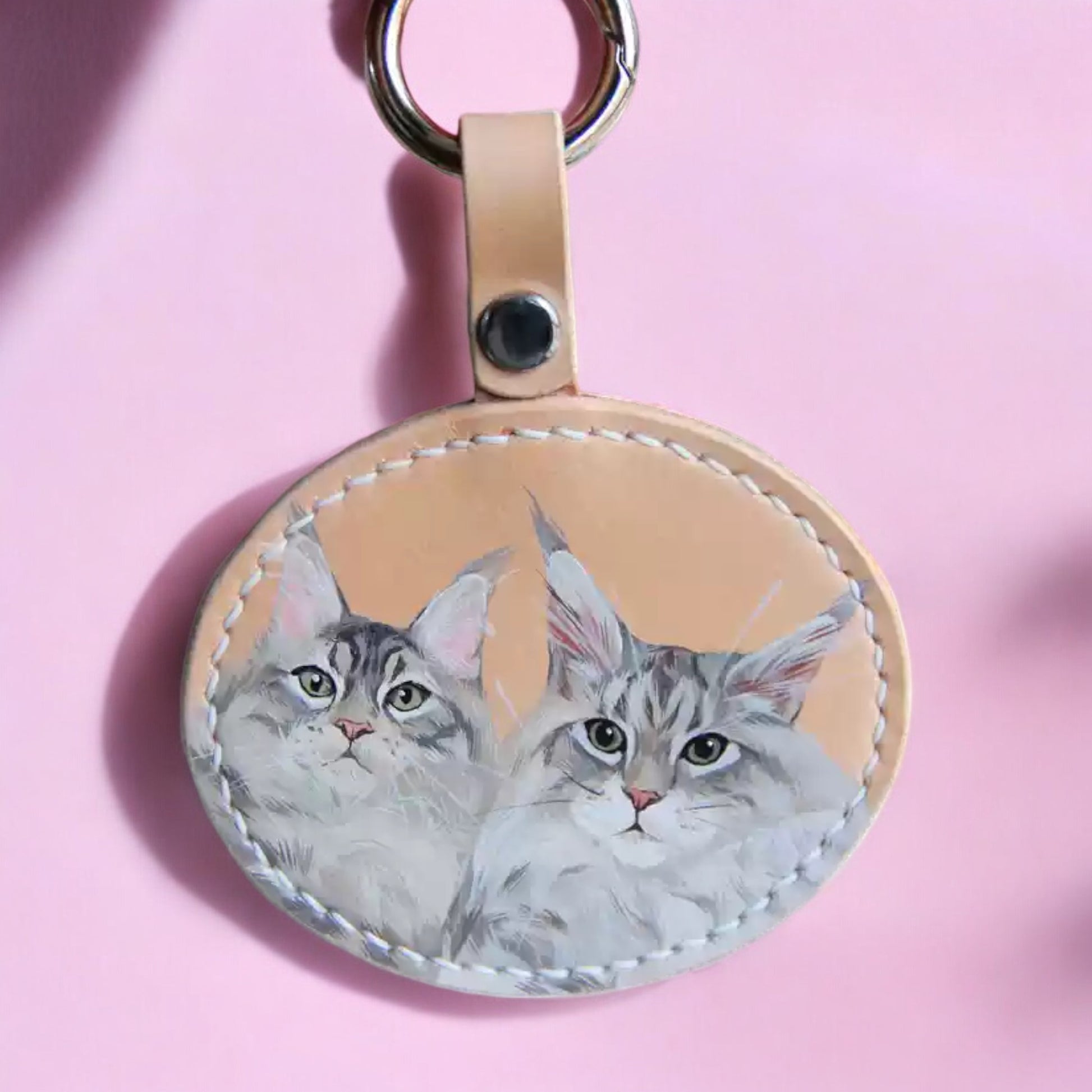 Custom hand-painted leather keychain with two realistic cat portraits, showcasing detailed brush strokes and personalized design.