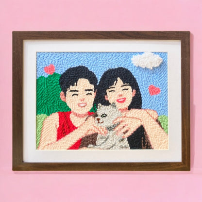 Custom punch needle portrait of a pet owner and their cat in a handmade frame, featuring bright, playful colors on a textured wool canvas.