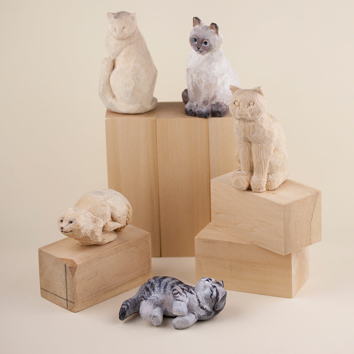 Collection of custom wood carved cat figurines displayed on wooden blocks