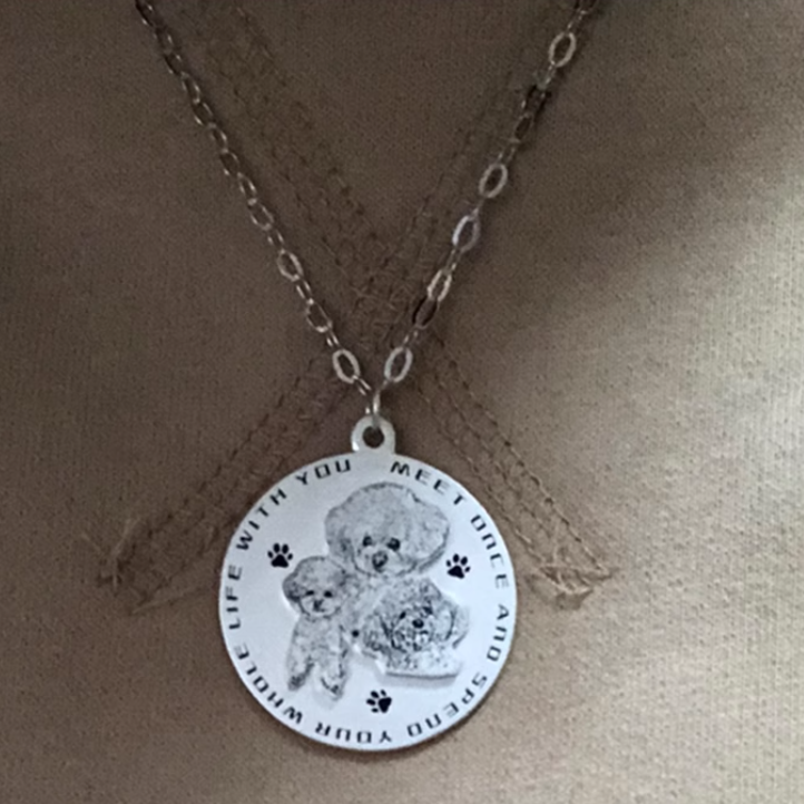 Double layer pendant necklace with two small dogs engraved, worn on a fabric surface.