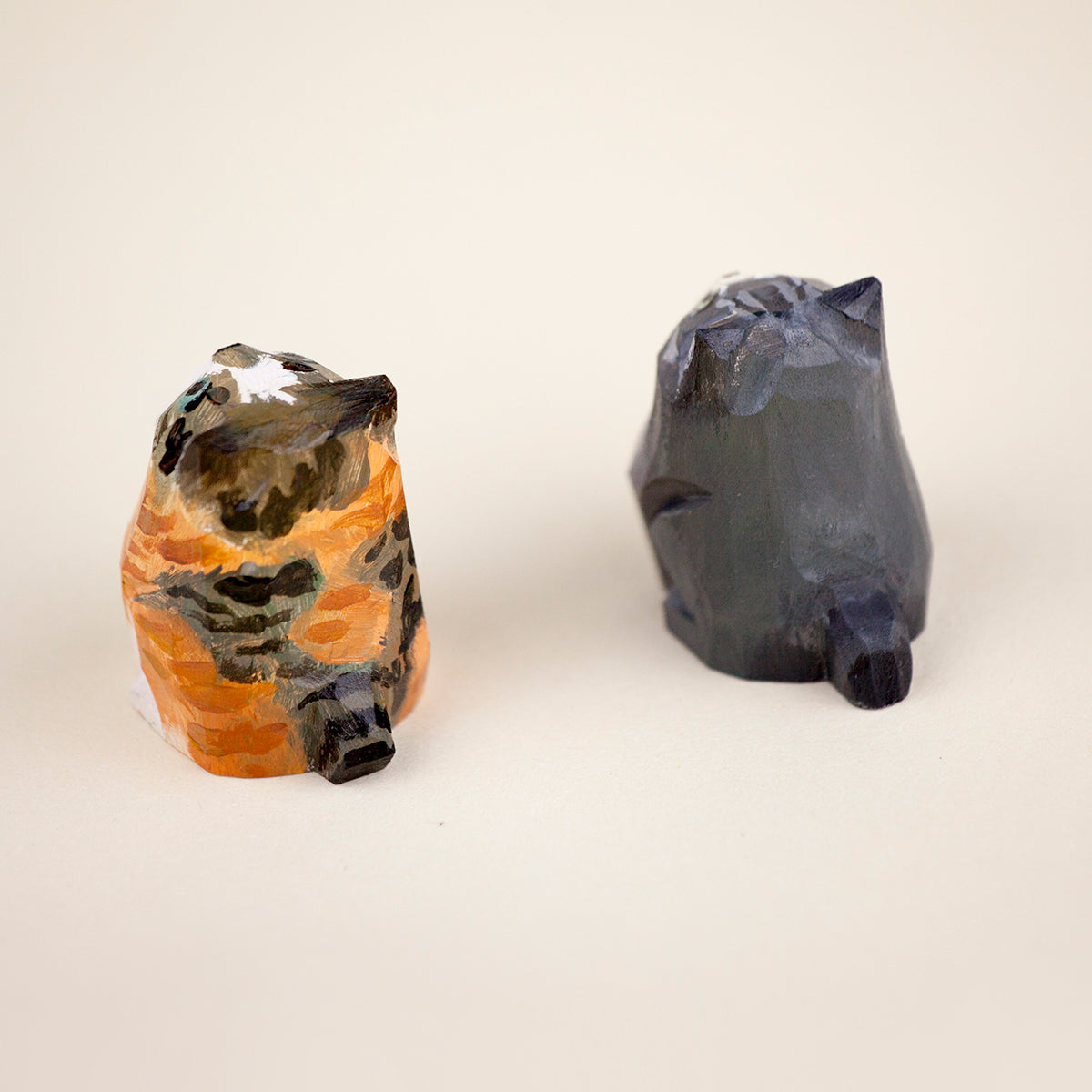 Rear view of two handcrafted cat figurines with detailed hand-painted designs, showcasing their tails and fur patterns.