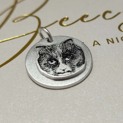 Sterling silver pendant featuring a cat's face, double layered, shown on a product card.