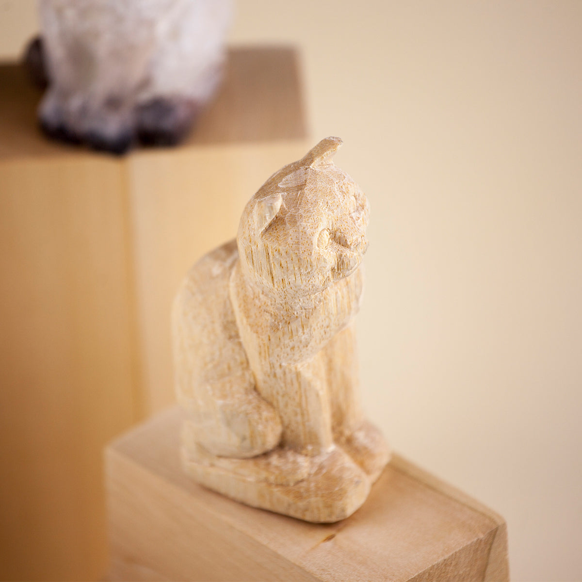 Unfinished wood carved cat figurine sitting on a wooden block