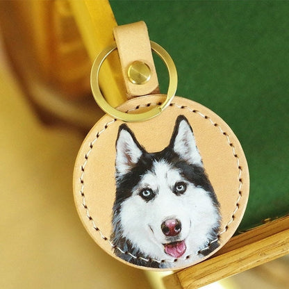 Handpainted leather keychain with a portrait of a husky dog, on a green background.